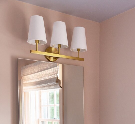 Three armed wall sconce above a bathroom mirror