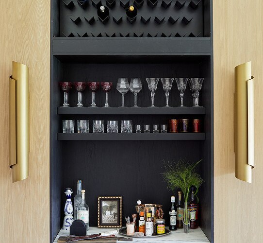 Large brass wall sconce flanking a built in bar cabinet