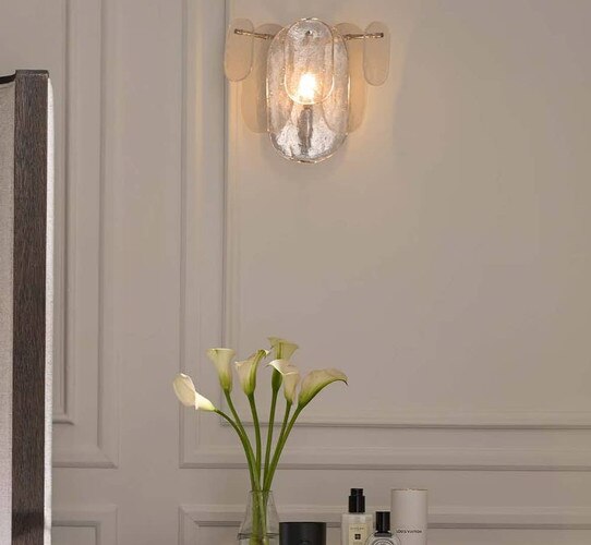 Glass sconce on a white wall with wanescotting