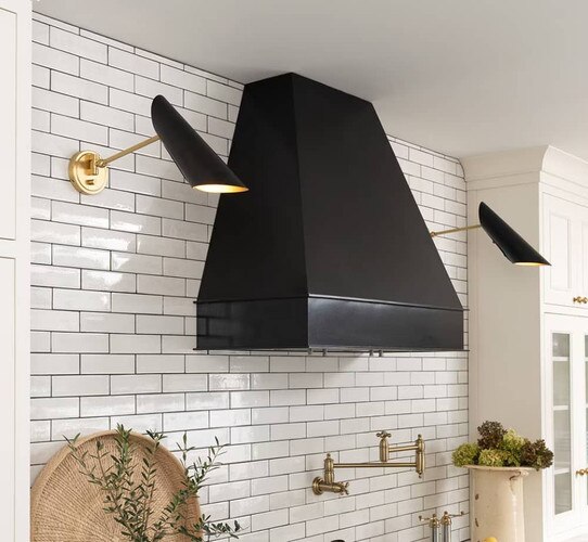 Oven hood flanked by two brass and black sconces