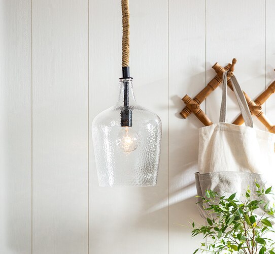 Hammered glass pendant with rope chair beside a wooden trellis with a canvas bag
