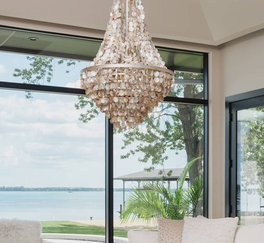 Shell chandelier in front of windows out toward a beach