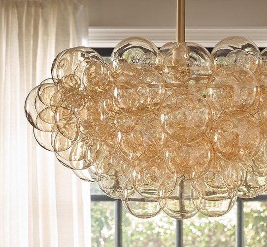 Ambered glass bubble chandelier in front of a window with a white curtain