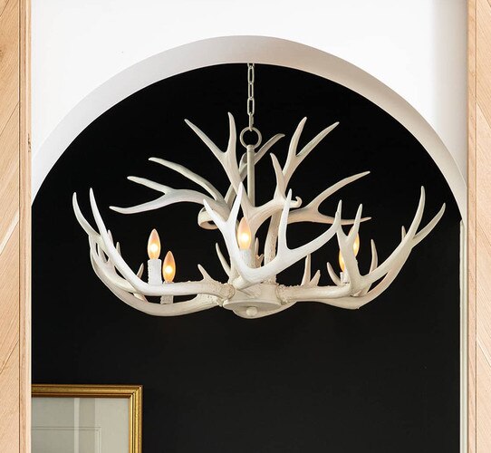 White antler chandelier in front of a black wall