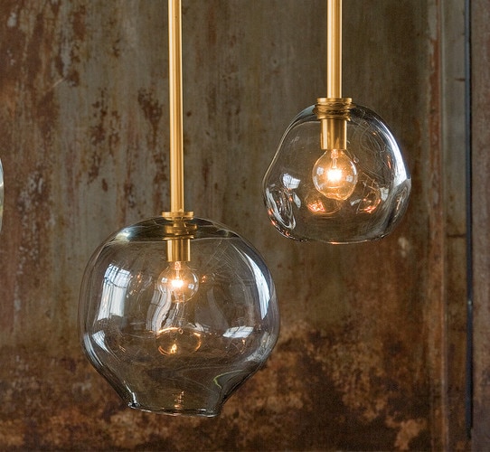 Molten glass pendant lights in front of a patinaed metal wall