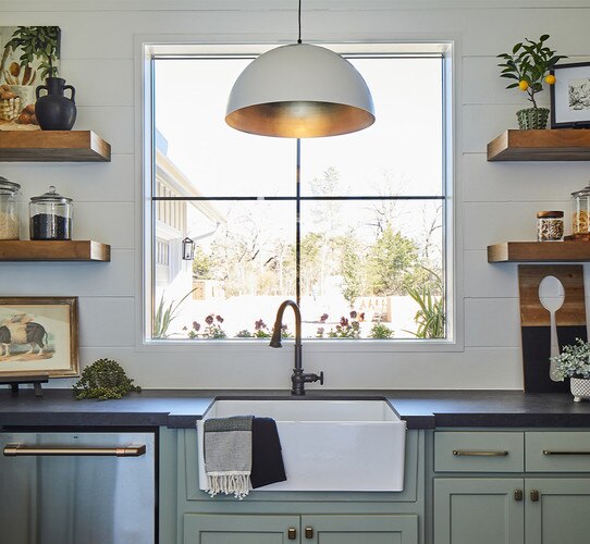 White and gold pendant light above a farmhouse sink