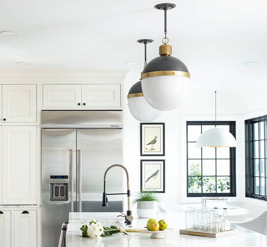 Large bronze and brass pendant lights above a kitchen island