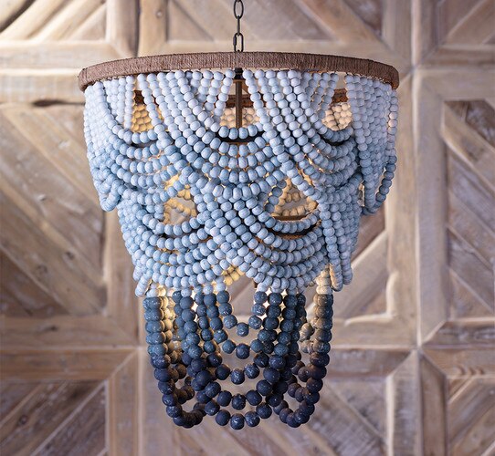 Blue and dark blue beaded chandelier in front of a textured wood wall