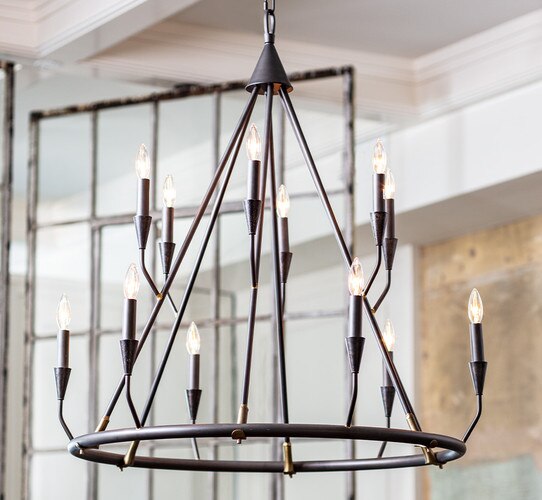 Two tiered metal chandelier with metal socket bodies protruding from the sides, hung in front of a swinging metal door