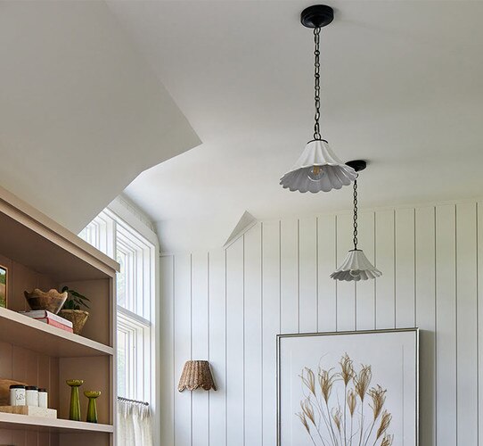 White ceramic pendant lights in a hallway with a picture frame and wooden shelf with decor