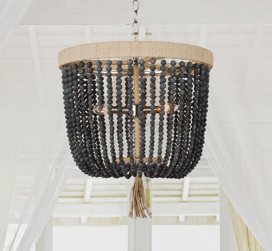 Wood beaded and rattan chandelier in front of a canopy bed