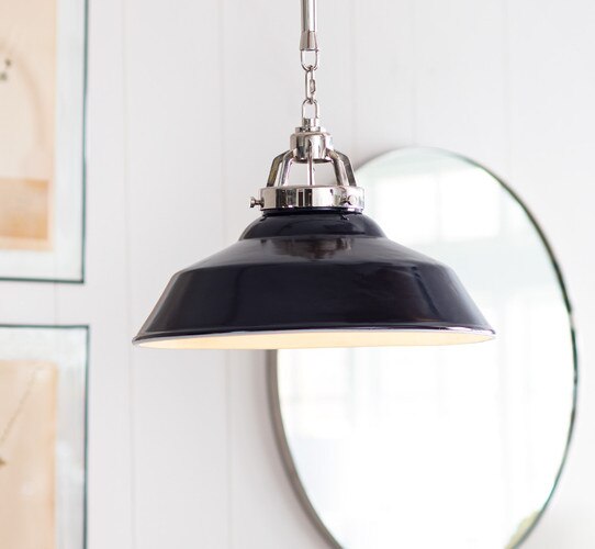 Navy and nickel pendant light in front of a circular mirror