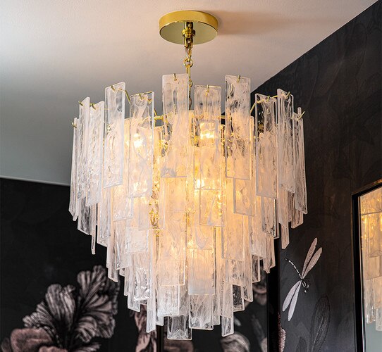 Tiered swirled glass chandelier in front of black and pink floral wallpaper