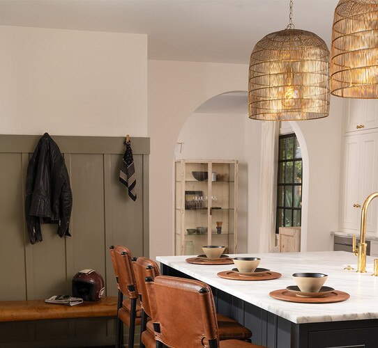 Brass metal cage pendants above a marble kitchen island