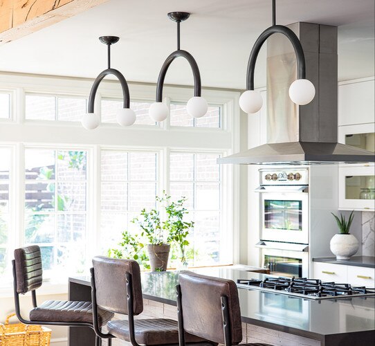 Curved bronze pendant lights with circular glass shades above a kitchen island