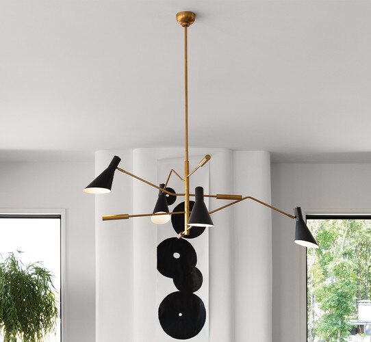 Black and brass multi-armed chandelier in front of a black and white abstract painting
