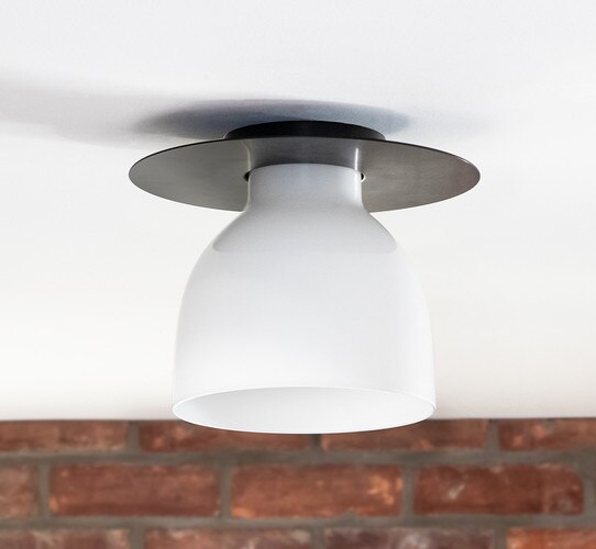 Bronze and milk glass flush mount in front of a brick wall