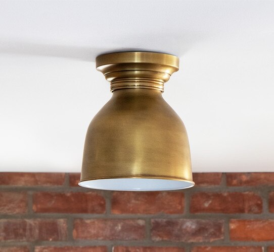 Brass flush mount in front of a brick wall