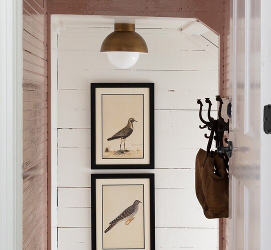 Brass and milk glass flush mount above two picture frames with bird drawings in them