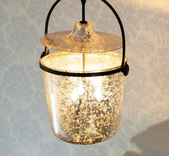 Antique mercury bell jar pendant in front of wall with white and light blue wallpaper of flowers