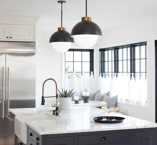 Two black and brass pendant lights over a kitchen island