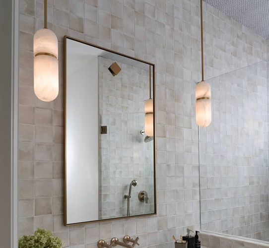 Alabaster pendants flanking a brass bathroom mirror