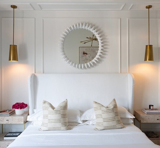 Two brass pendant lights above nightstands in a bedroom