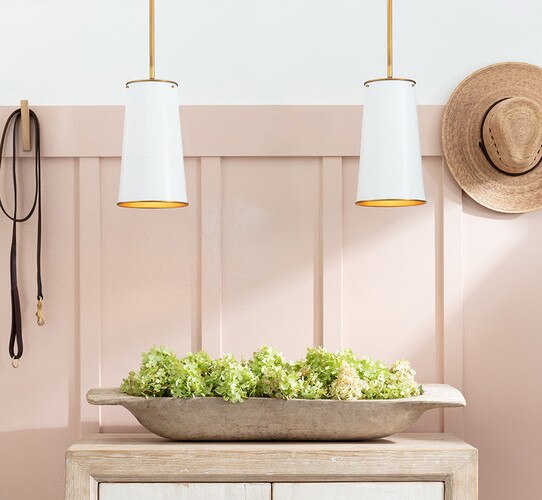 Two white and brass pendant lights above a bowl filled with flowers