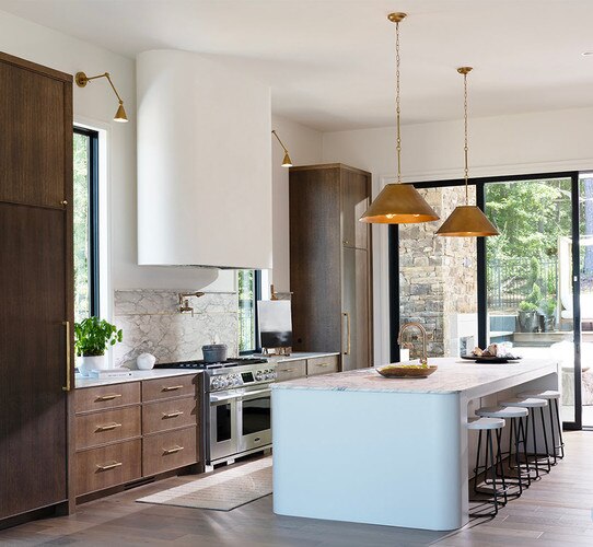 Modern kitchen with brass pendant lights above a marble kitchen island