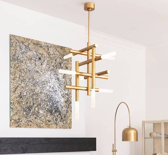 Brass chandelier hung in front of a large picture frame above a mantle