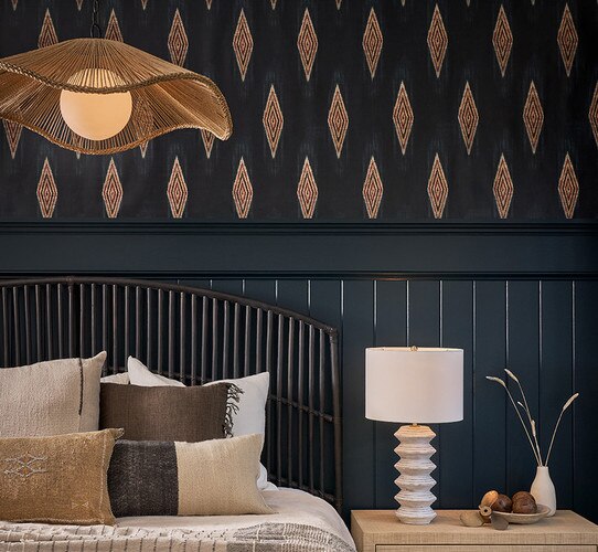 Large wicker pendant light above a bed in a coastal bedroom