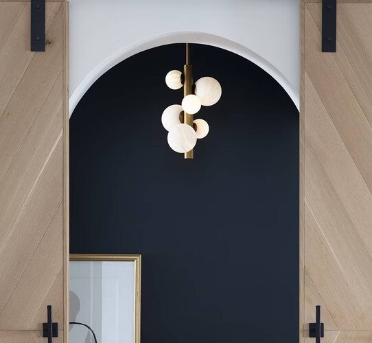 Vertical brass and alabaster pendant in front of a blue wall