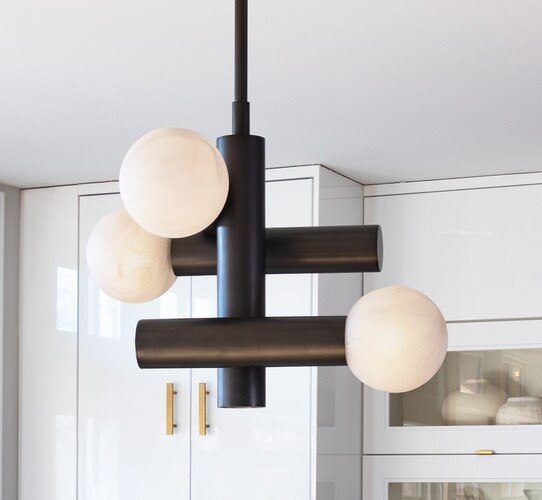 Black and alabaster structural pendant in front of white kitchen cabinets