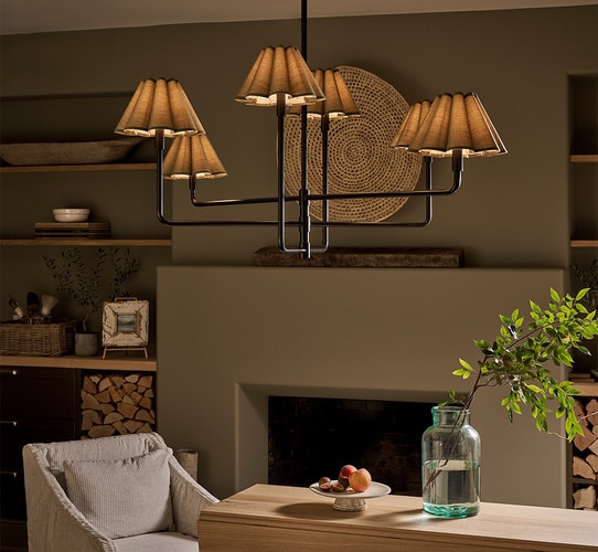 Black multi armed chandelier above a wood dining table with a tray of peaches and a vase of water