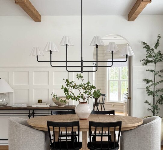 White and black chandelier above circular wood dining table