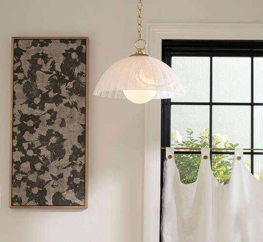Milk glass dome pendant beside a frame of black and gray art next to a window