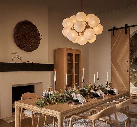 Swirl glass bubble chandelier above a set dining table with garland and candlesticks