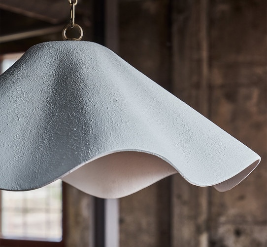 Scalloped pendant light in front of distressed wall