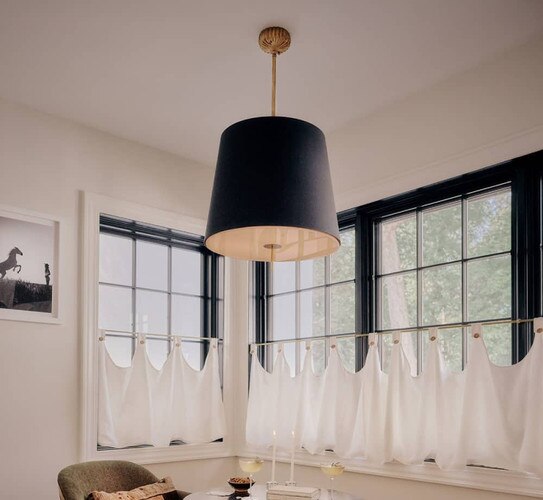 Black and gold pendant in front of bay windows