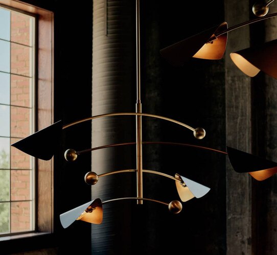 Brass and black chandelier in front of a lit window