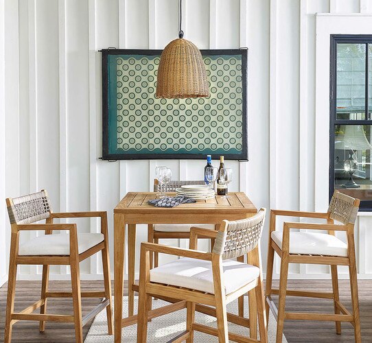 Outdoor patio with wooden bar table, chairs and a woven pendant light