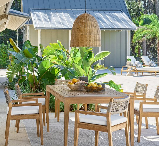 Patio with wood dining table, chairs and a large woven pendant light