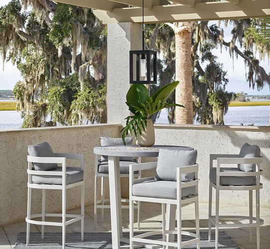 Patio with gray bar top table and chairs with a willow tree behind it
