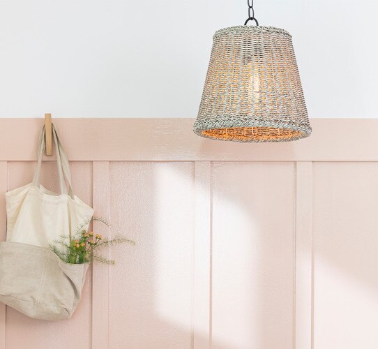 Pink wall with a gray woven pendant light and a canvas bag hanging on a hook
