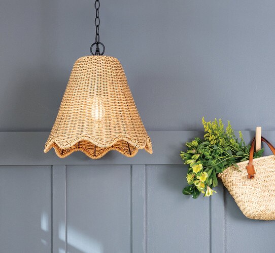 Woven pendant light in front of a blue wall with a hook hanging a basket of flowers