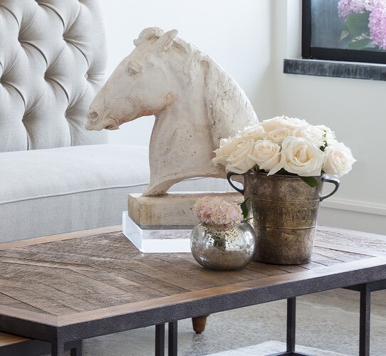 Antique mercury votive next to a vintage bucket and ceramic horsehead statue