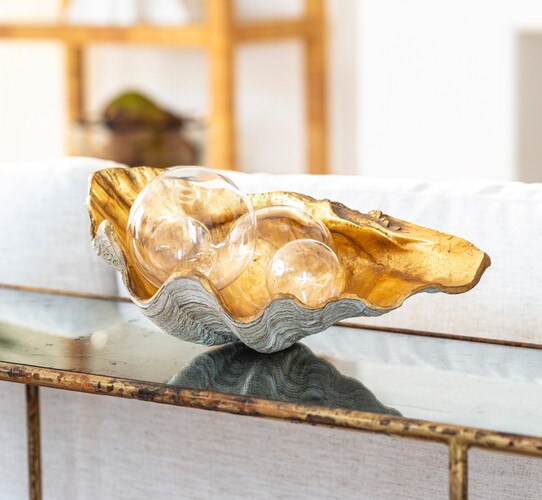Gold clam bowl with various sized glass bulbs resting inside
