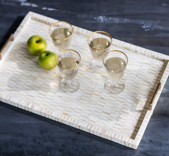 Bone and brass tray with four champagne glasses and two apples on top