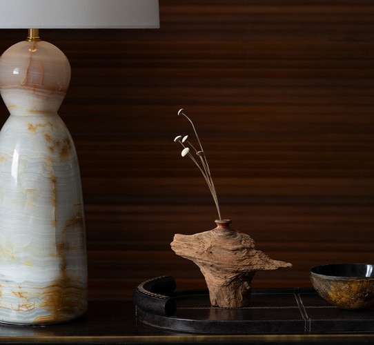A polished horn and brass bowl on a tray beside a jade lamp
