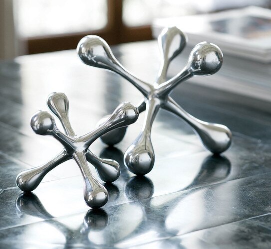 Two polished nickel jacks, one smaller, on a metal table